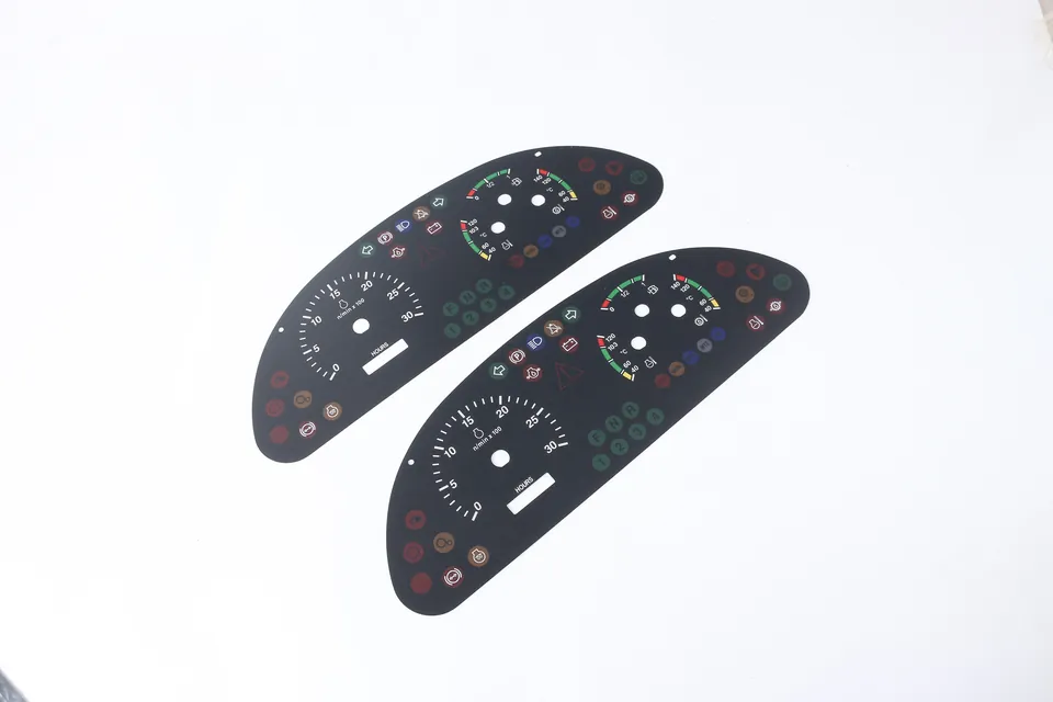 Two complete black automotive instrument overlays with gauge scales, indicator legends, apertures and mounting holes